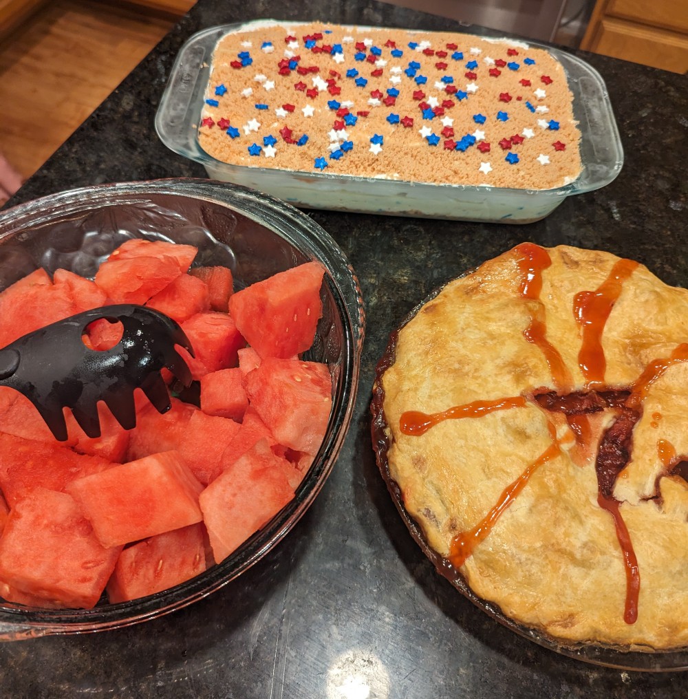 Bowl of watermelon, patriotic lush cake, and strawberry pie