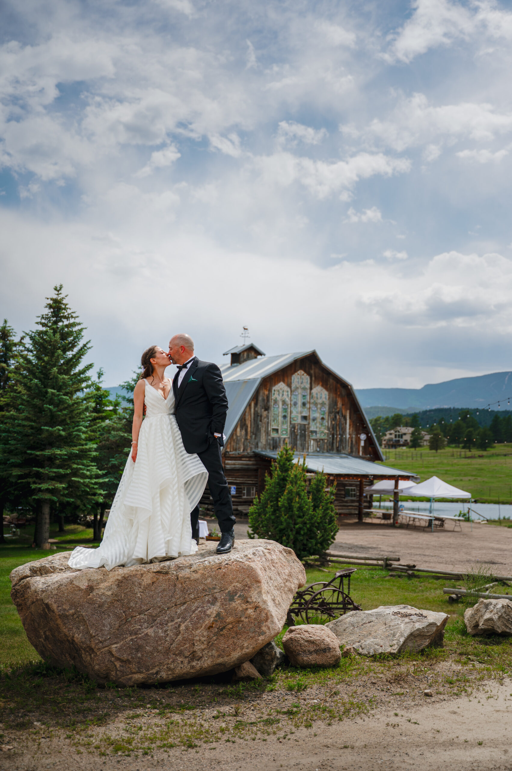 Laura and Mike on a rock outside a barn in wedding attire
