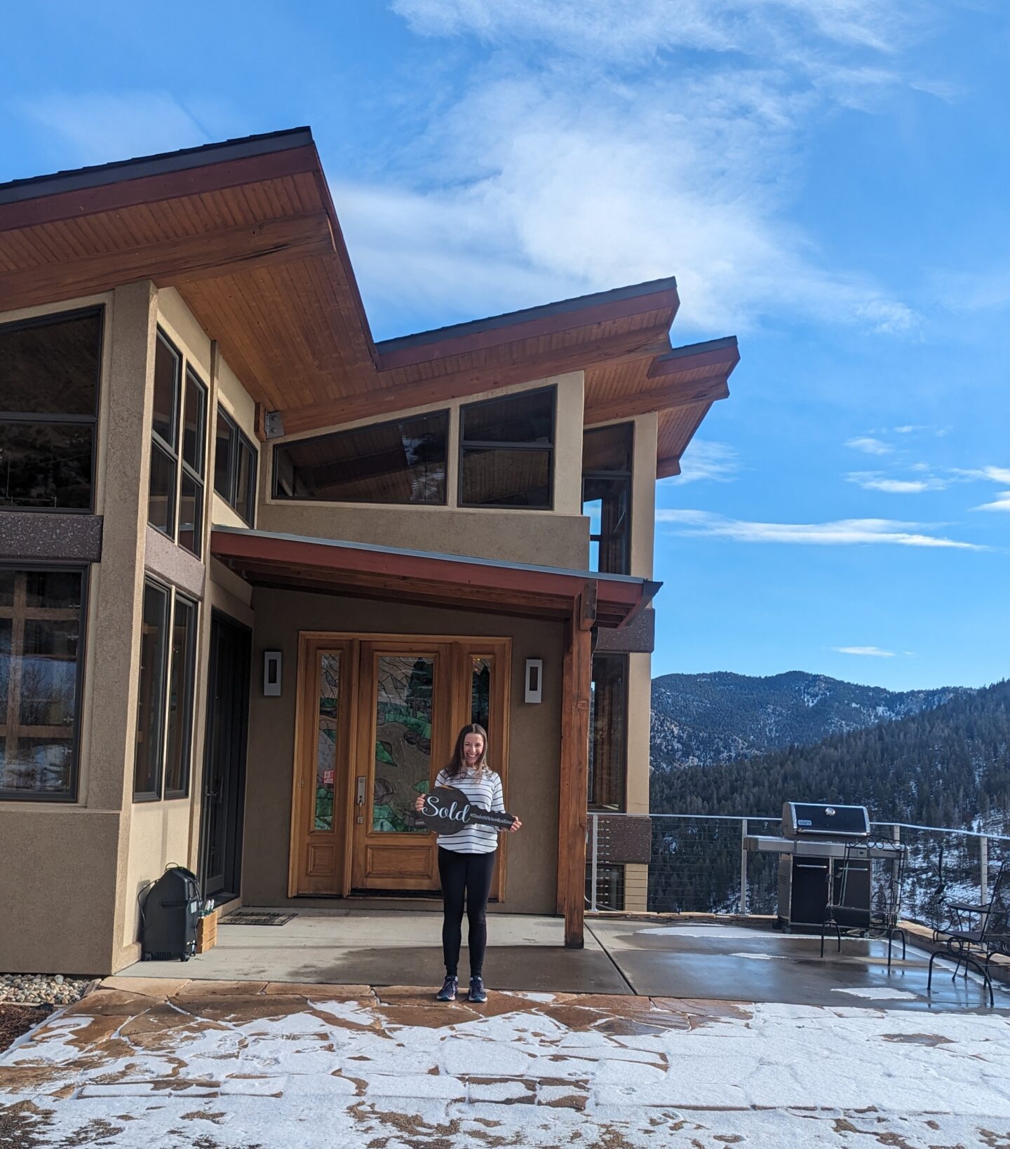 Laura standing in front of her new house with a "sold" sign