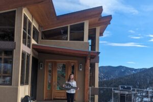 Laura standing in front of her new house with a "sold" sign
